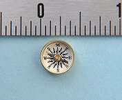 Small Military Special Forces Survival Button Compass next to an inch scale